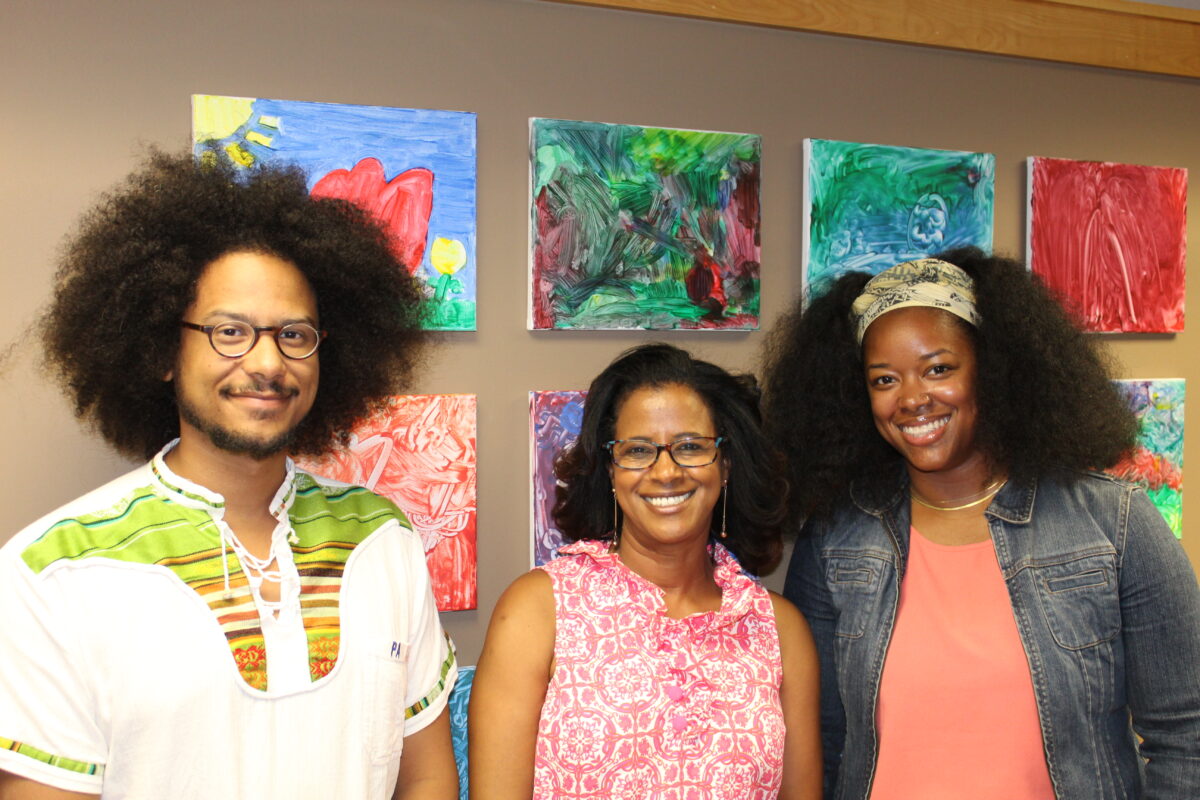 WFM staff and uCode Girl CEO Bethlehem Gronneberg standing and smiling in front of a wall of art pieces