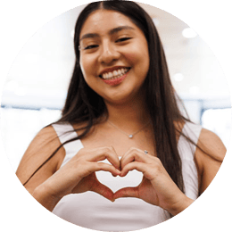 A young woman making a a heart symbol with her hands, smiling